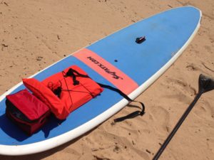 SUP Board, Paddle, Life jacket and water on sandy beach