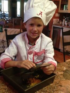 Wee Chef with Alabama Chef's Hat grating cheese Wee Chef with Alabama Chef's Hat grating cheese