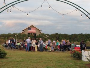 Weeks Bay Plantation barn with American Flag, lots of people waiting for concert www.diningwithmimi.com