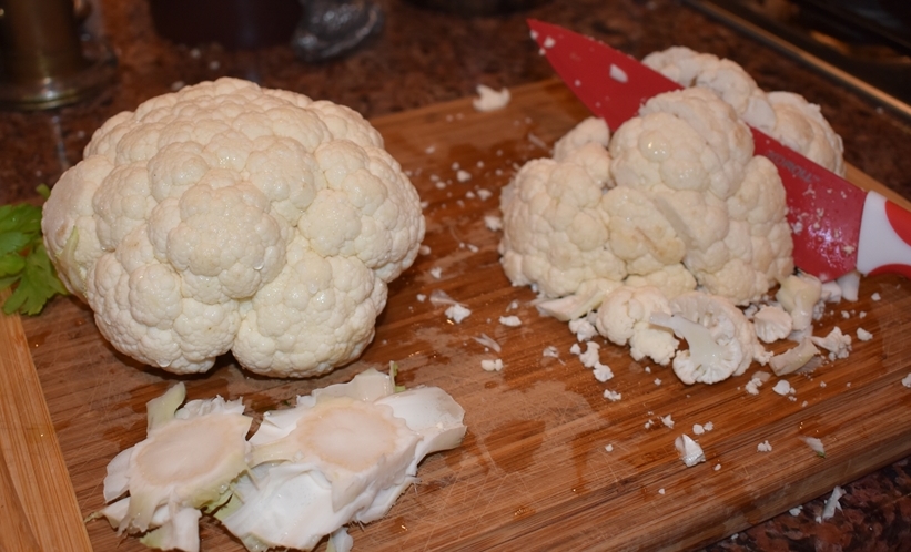 Cutting board with cauliflower being cut into smaller pieces Cauliflower Comfort Soup- Heals What Ails Ya' www.diningwithmimi.com