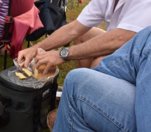 Man cutting large hunk of cheese with wine opener at my Hip Fairhope Outdoor Event www.diningwithmimi.com