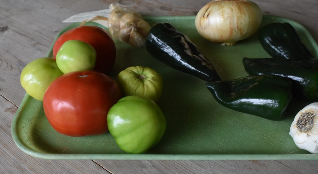 Tray loaded with fresh tomatoes, tomatillios, poblano peppers, onion and garlic for Smoky Roasted Poblano, Tomatillo and Tomato Salsa www.diningwithmimi.com