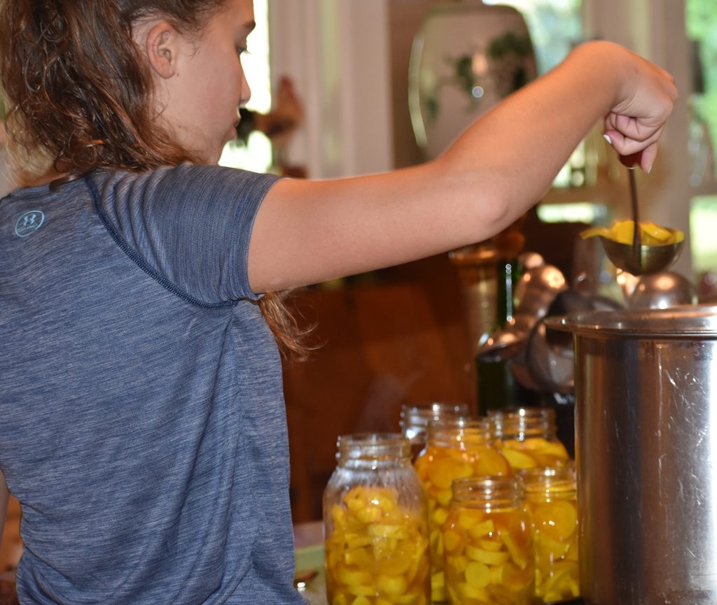 Young girl adding squash pickles to canning jars My Fearless Sous Chef in Training www.diningwithmimi.com