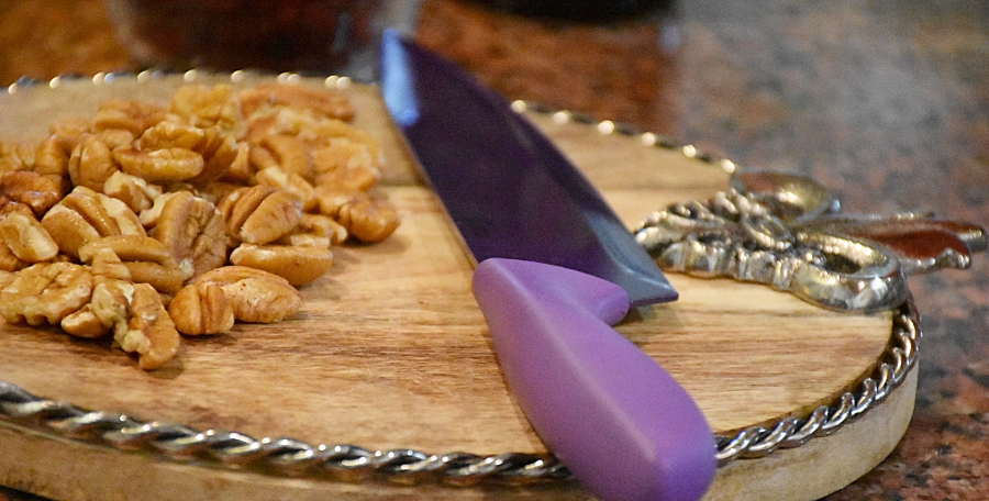 Pecans on cutting board with fleur de lis and purple knife www.diningwithmimi.com