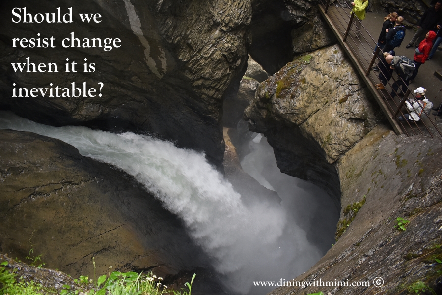 Overhead of Large cave waterfall with people near rail in Switzerland- Should we resist change www.diningwithmimi.com